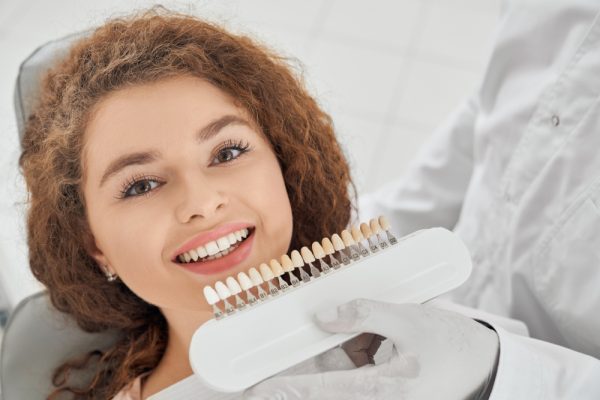 woman-smiling-while-male-dentist-keeping-teeth-color-range (1)